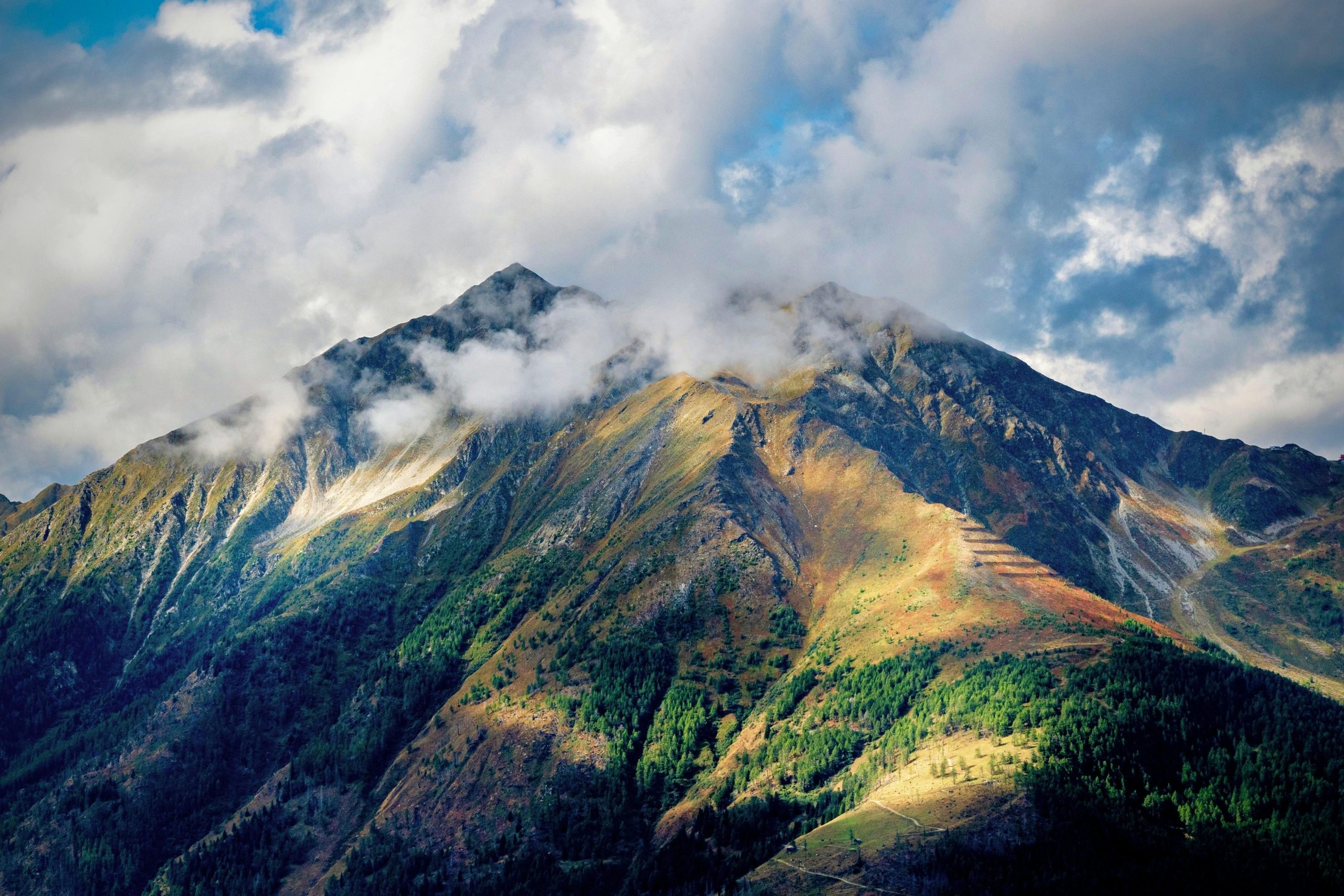 Stunning view of a mountain peak with clouds and sunlight highlighting the terrain.